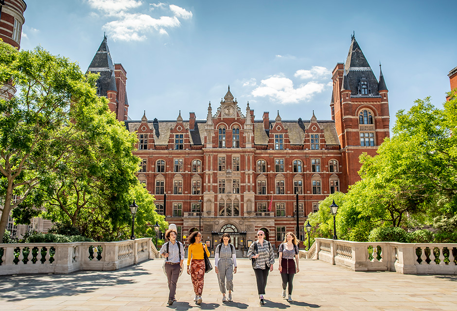 A group of students walk together on a bright sunny day, with the RCM main campus, a grand historic building, visible in the background.